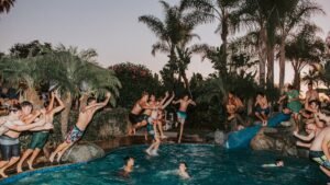Guests jumping into a resort pool at dusk, lively nightlife atmosphere