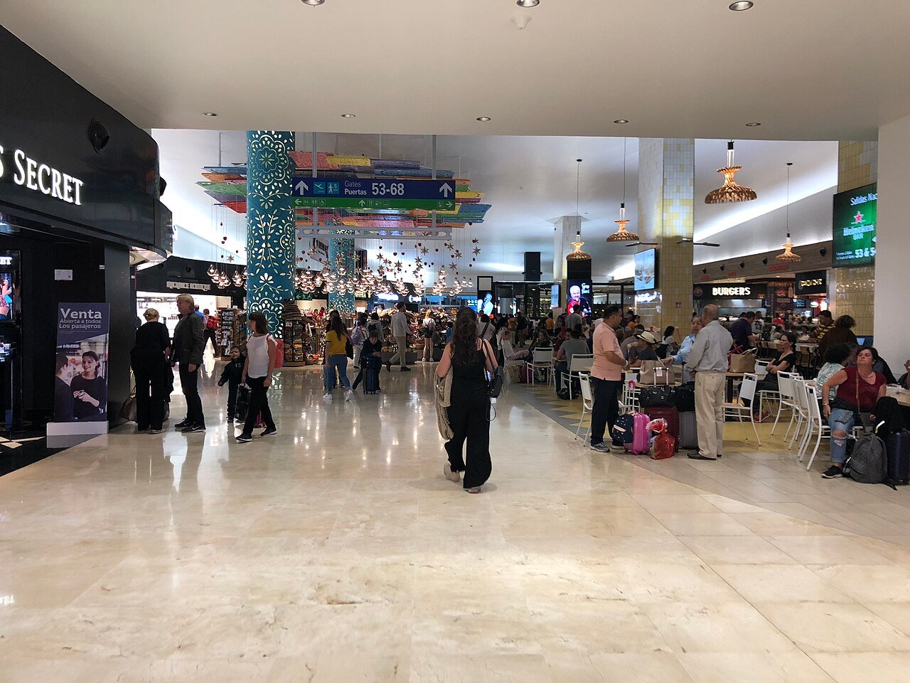 Pasajeros con equipaje en la zona de tiendas del aeropuerto de Cancún
