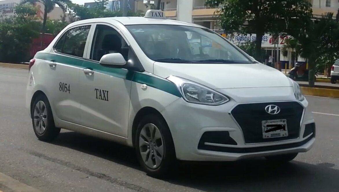 A white taxi sedan photographed on a street in Cancun, Quintana Roo, Mexico