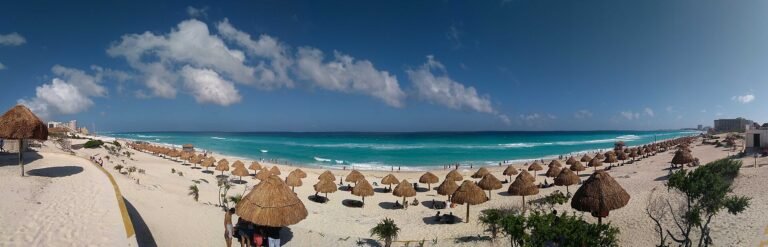 Wide panorama of Playa Delfines in Cancun with palapas and the Caribbean Sea