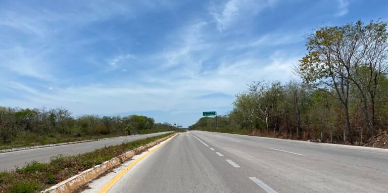 Empty two-lane highway through the Yucatan countryside with a green route sign