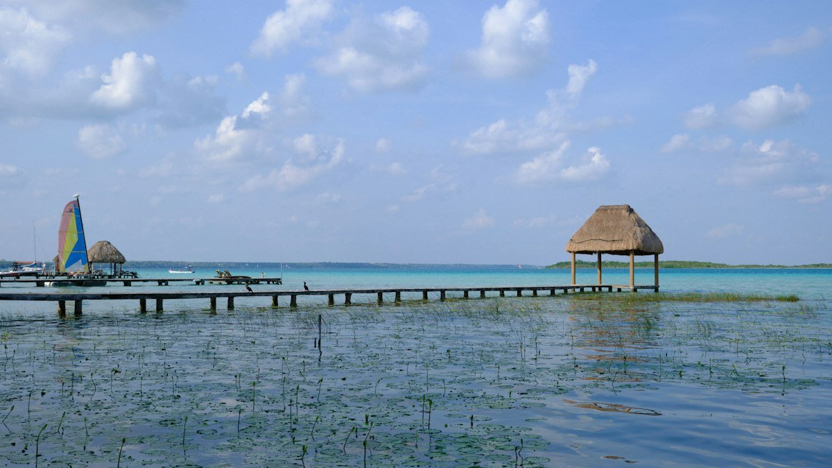 Dock with a thatched palapa roof and sailboats on Bacalar Lagoon, Quintana Roo