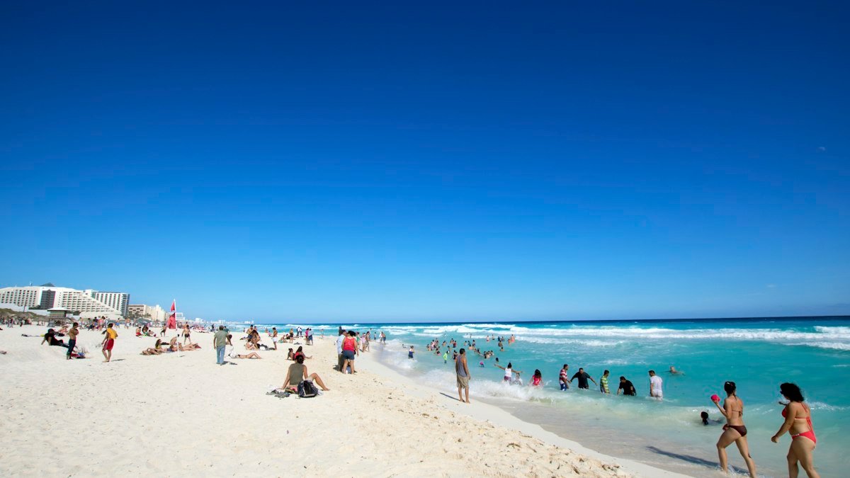 Group of travelers standing on the sand of a Cancún beach