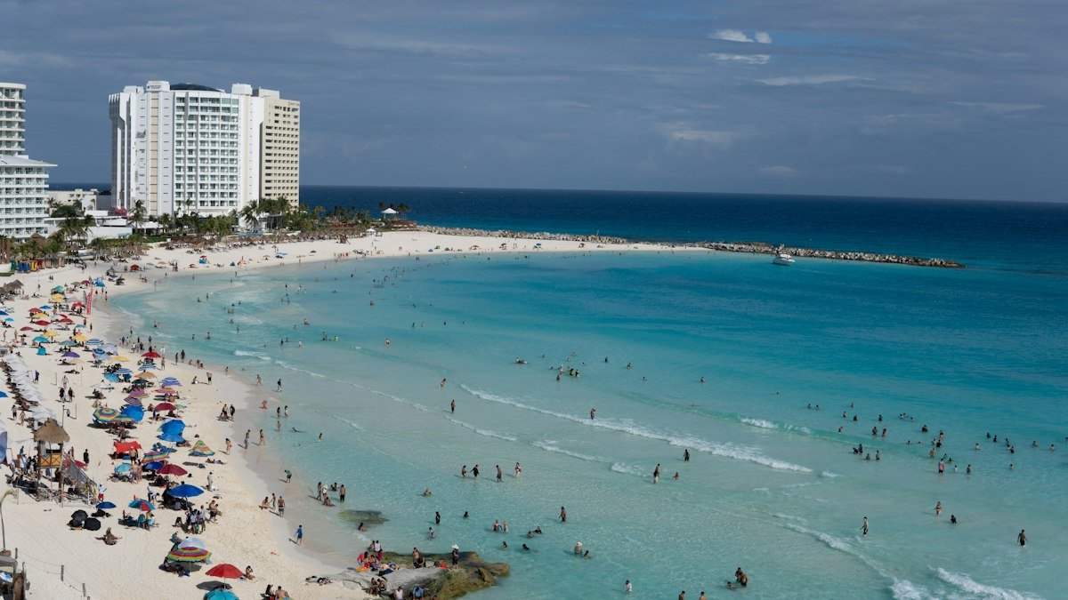 Crowded beach in Cancún with swimmers and sunbathers during the holiday season