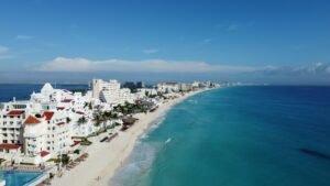 Aerial view of a Cancún Hotel Zone beach with hotels and the city behind it
