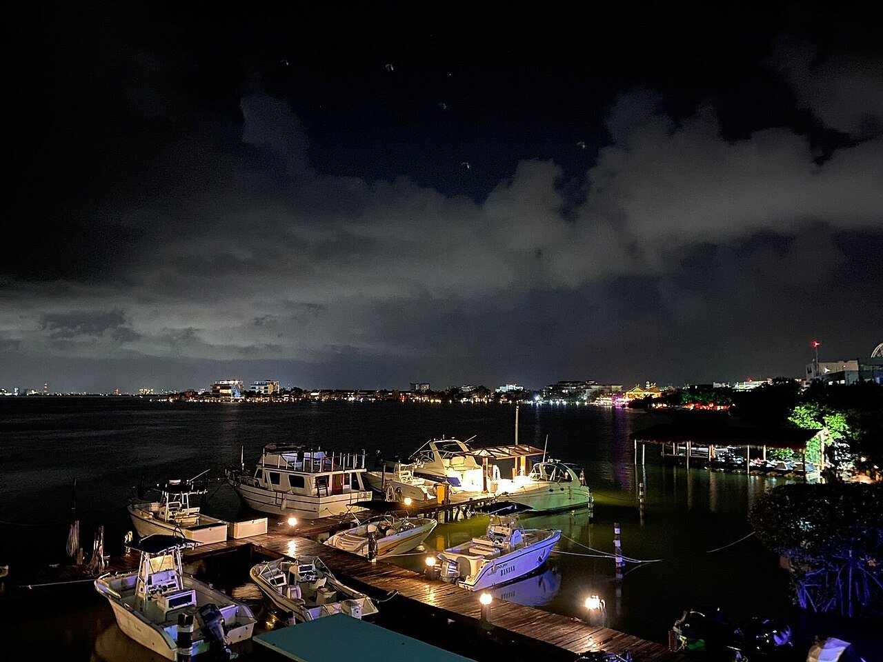Lanchas amarradas en el mar de Cancún de noche bajo un cielo nublado