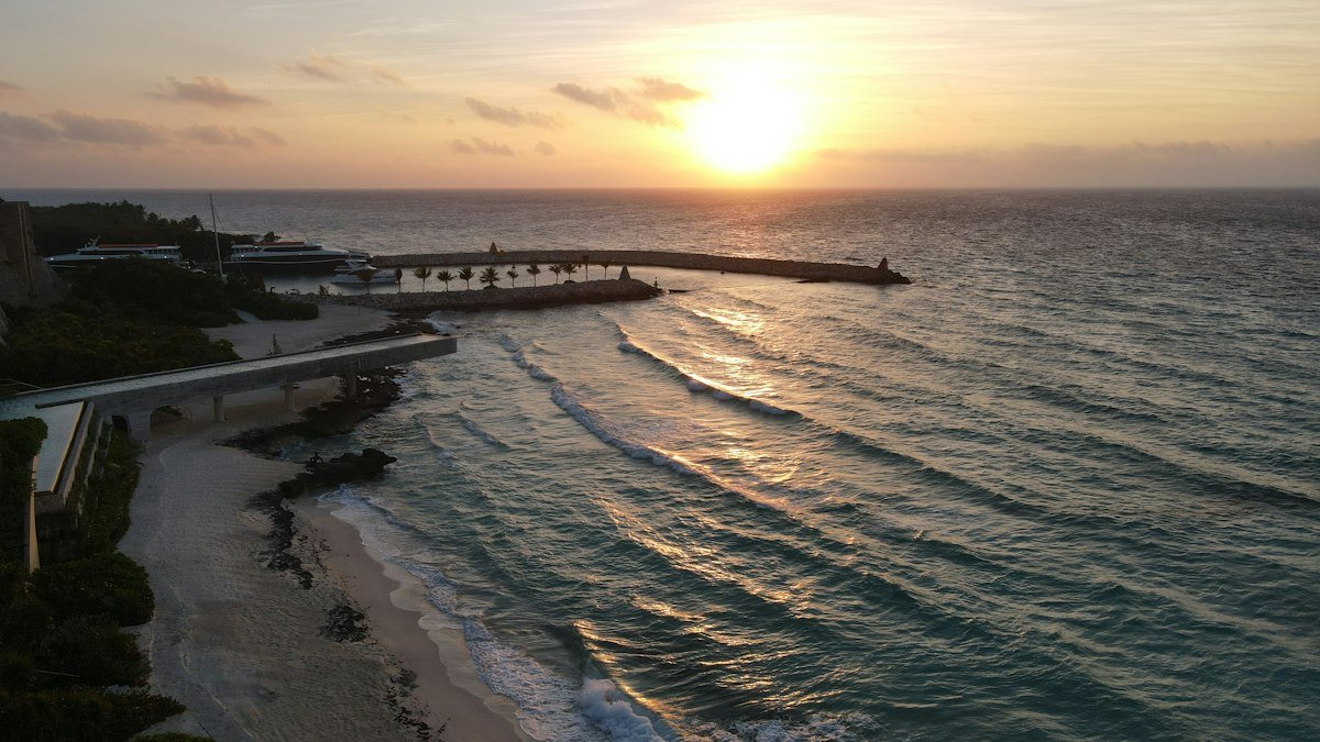 Calm Caribbean and a sandy beach in front of a Cancún oceanfront resort in low golden light