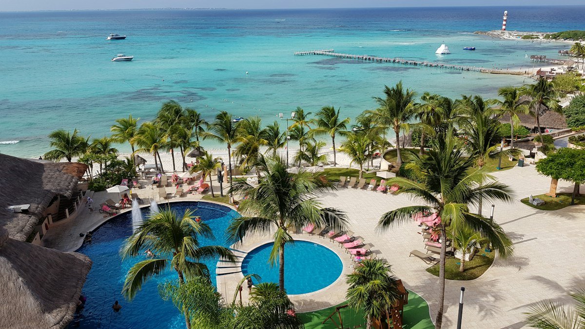 Palm trees beside a pool and the Caribbean in Cancún on a sunny March day