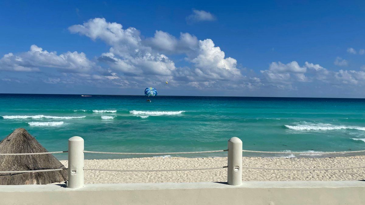 Sunny beach in Cancún with a parasail in the sky over the turquoise sea