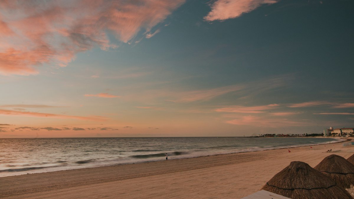 Wooden dock reaching into the water in Cancún under a red evening sky