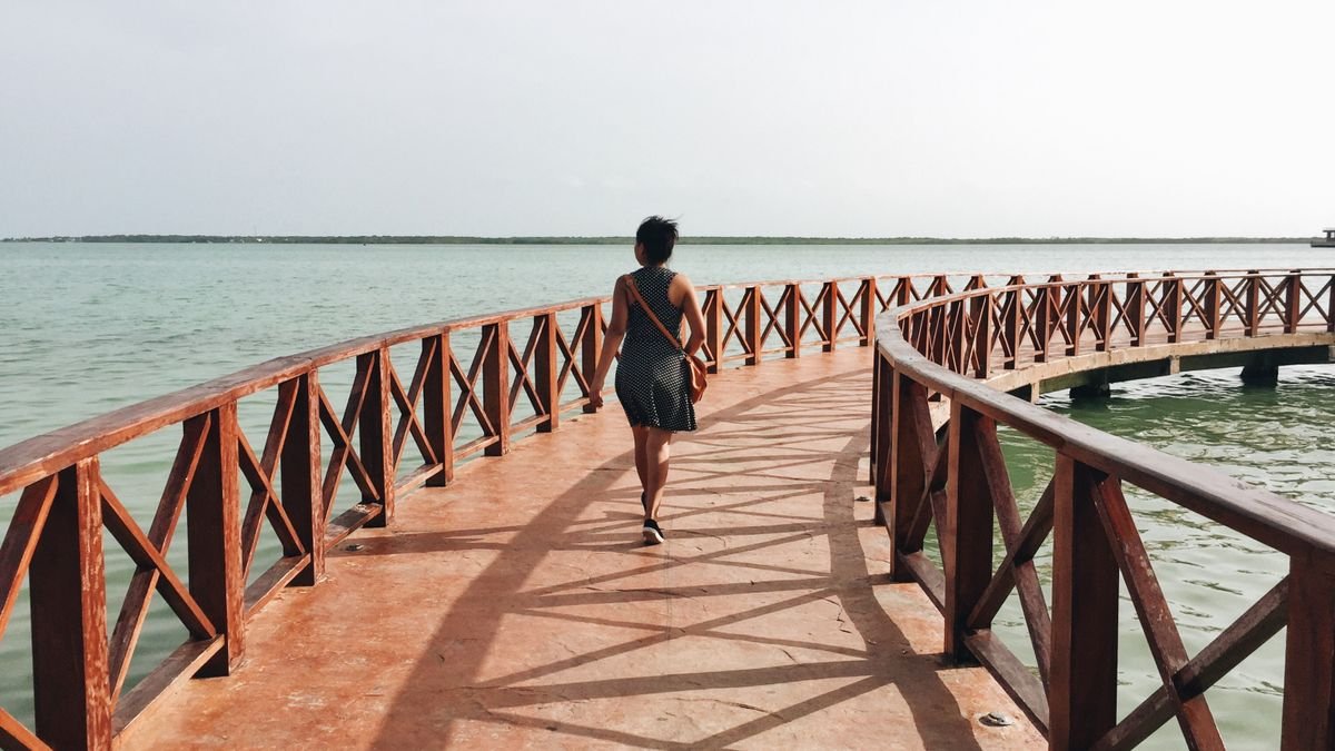 Woman walking along a wooden pier over the bay in Chetumal, Quintana Roo