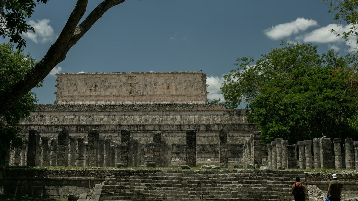 Group of visitors standing in front of a stone structure at Chichén Itzá, Yucatán