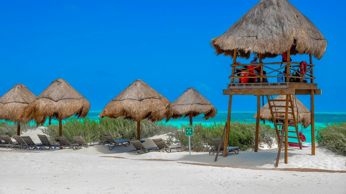 Beach umbrellas and a lifeguard tower on the turquoise coast of Costa Mujeres, Quintana Roo