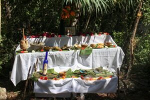 Altar de Hanal Pixán con mantel blanco, comida, frutas y flores montado al aire libre en la Península de Yucatán