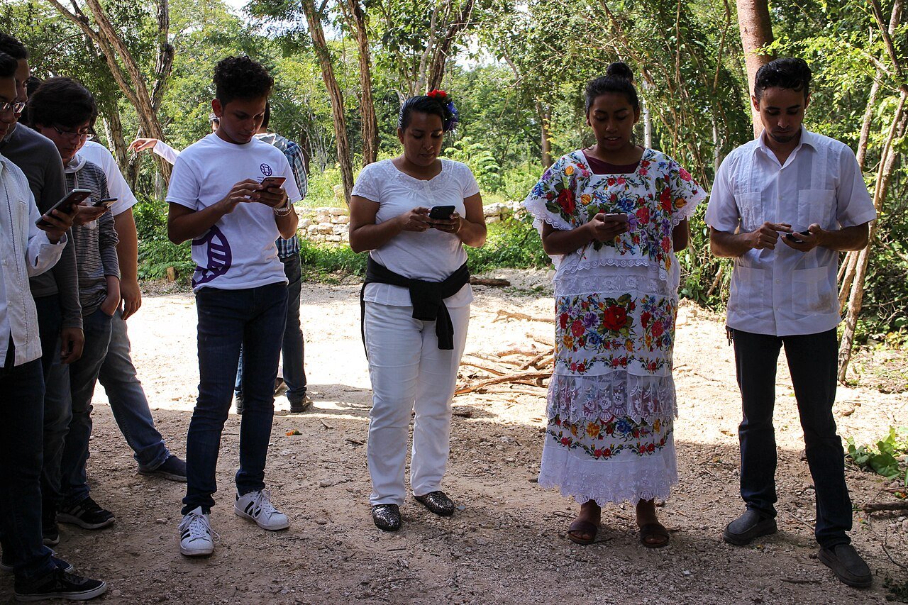 Grupo de personas con ropa tradicional yucateca durante un rezo de Hanal Pixán
