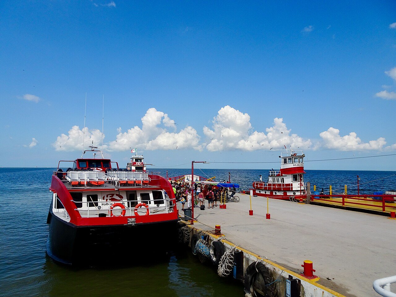Red and white passenger ferries tied up at a concrete pier at a ferry terminal in Quintana Roo, Mexico