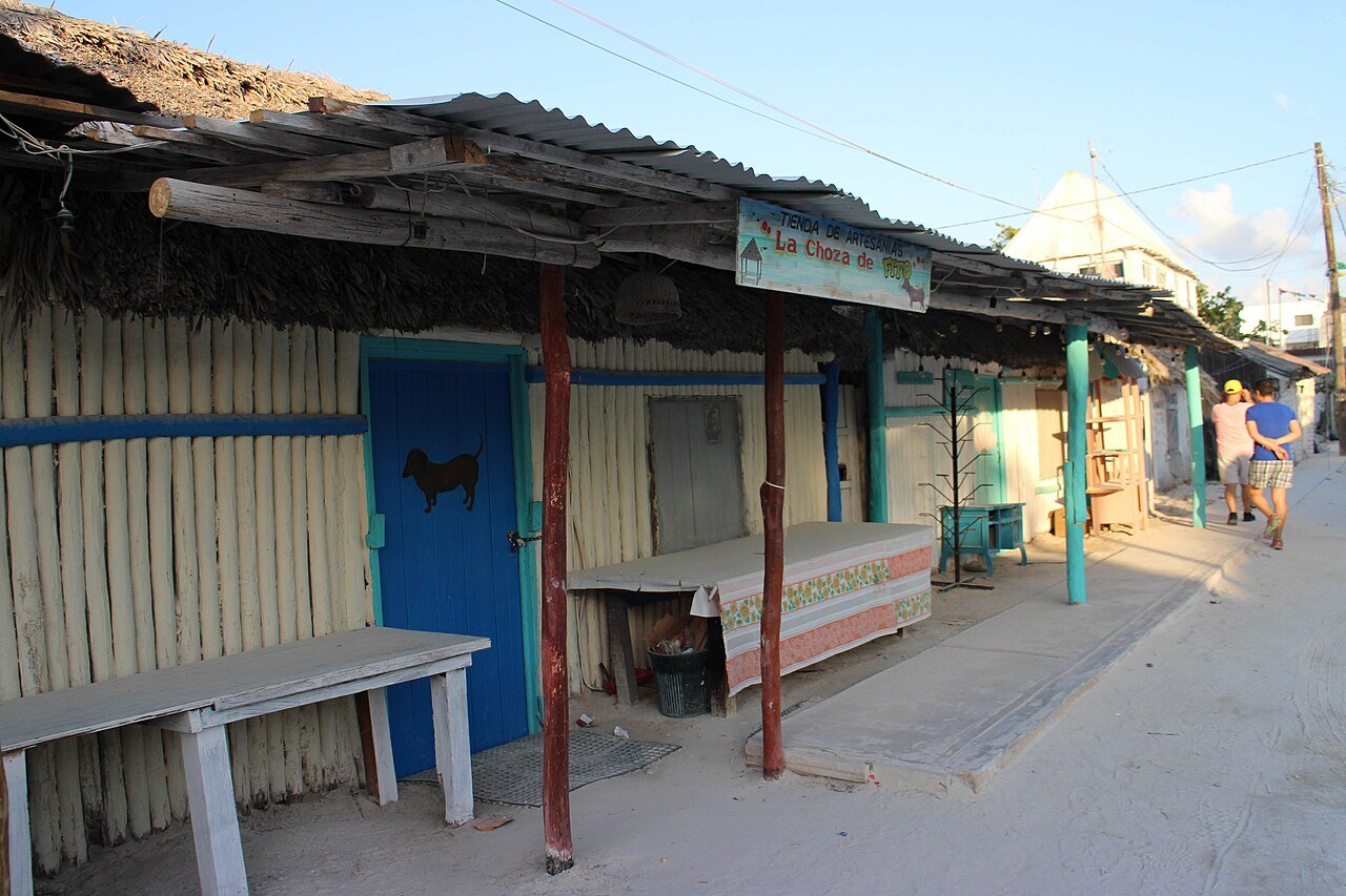 Unpaved sand street lined with small wooden shopfronts on Isla Holbox, Quintana Roo