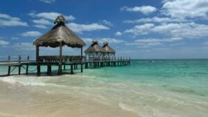 Playa Mujeres beach with turquoise water, a wooden pier and palapa umbrellas north of Cancún